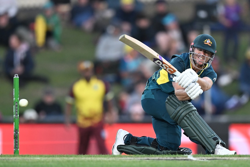 Australian cricketer David Warner grimaces as he sweeps the ball behind him during a T20 international. 
