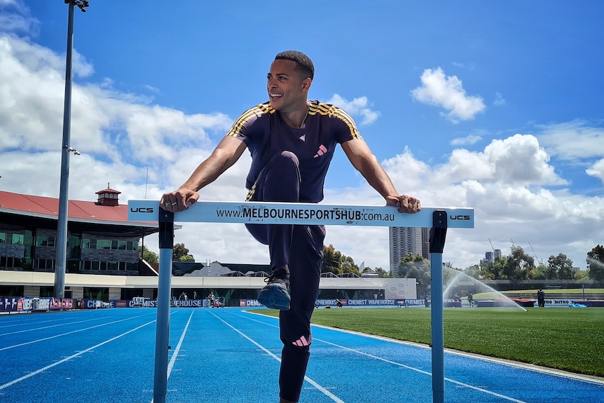A man poses on a running hurdle