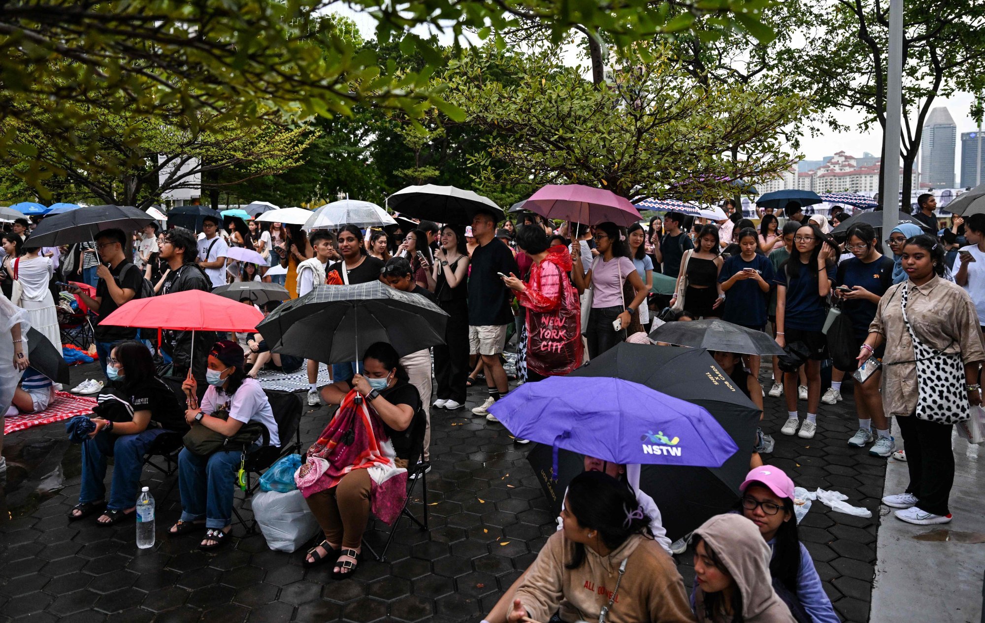 Fans of Taylor Swift, also known as Swifties, stand under umbrellas during the pop star’s Eras Tour concert as they listen to the performance from outside the National Stadium in Singapore on Thursday. Photo: AFP