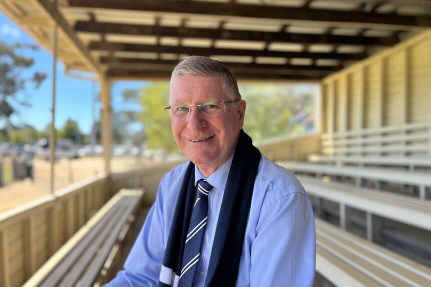 Denis Napthine sitting in a sports stand while smiling at the camera