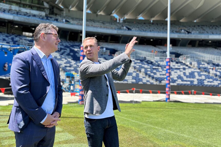 Two men standing on a sports field while talking to one another