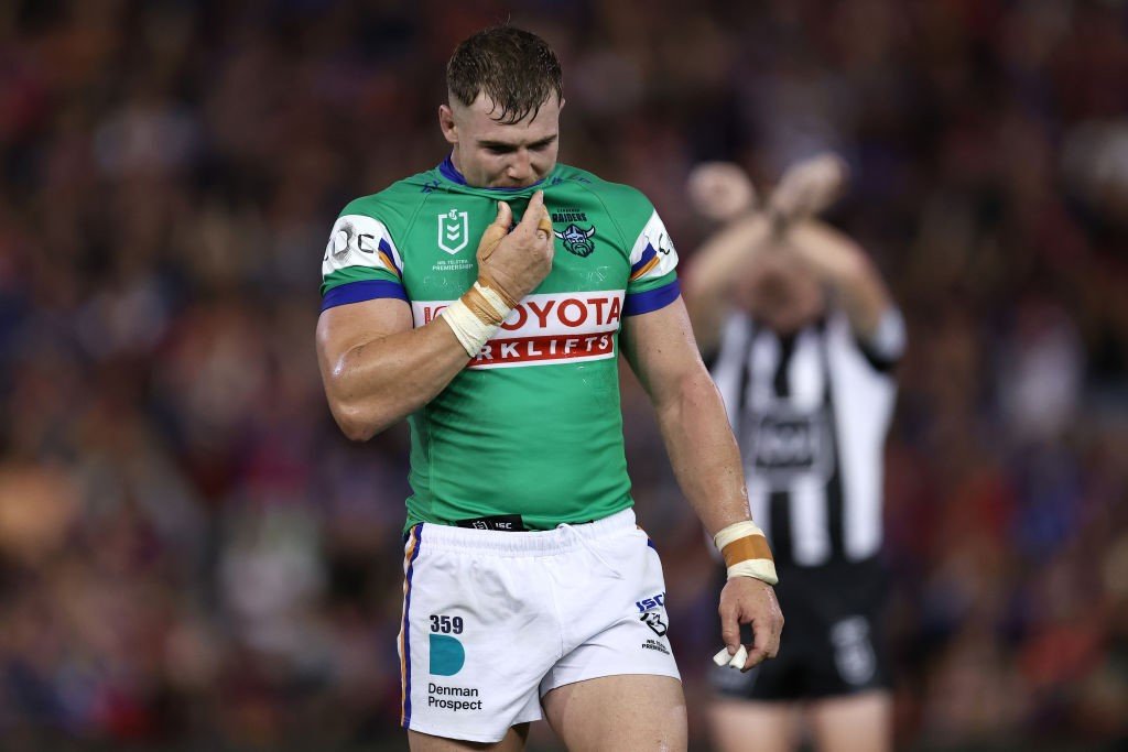 Canberra Raiders' Hudson Young walks off as the referee signals a cross with his arms behind him.