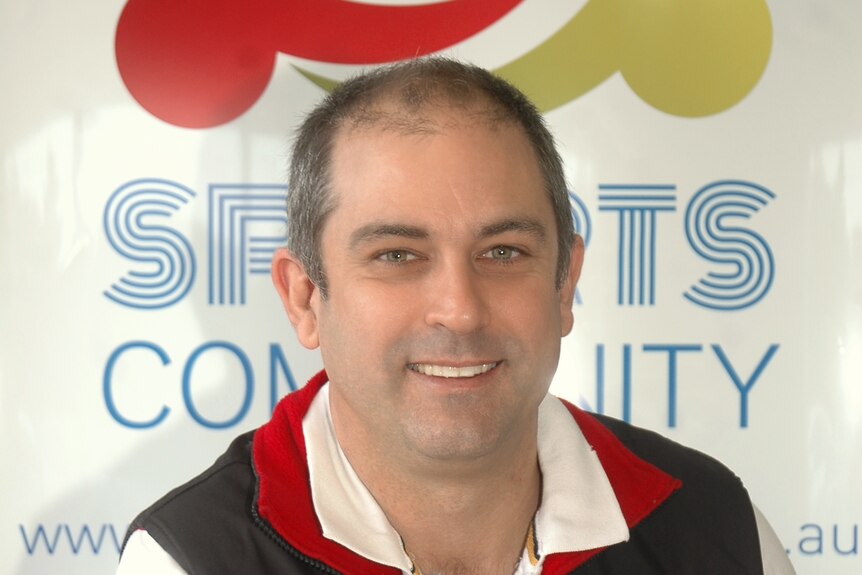 A man with thinning grey hair smiles at the camera