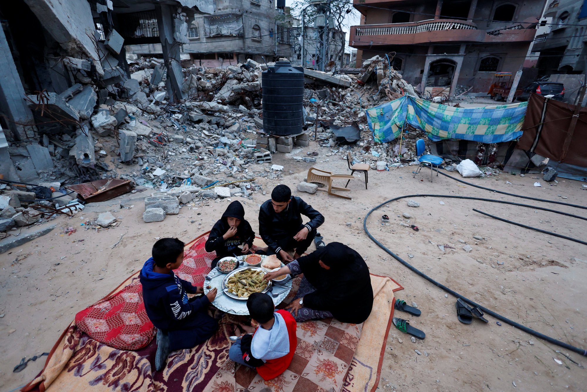 Members of a Palestinian family break their fast near the rubble of their destroyed house during the holy month of Ramadan in Rafah on March 21. Photo: Reuters