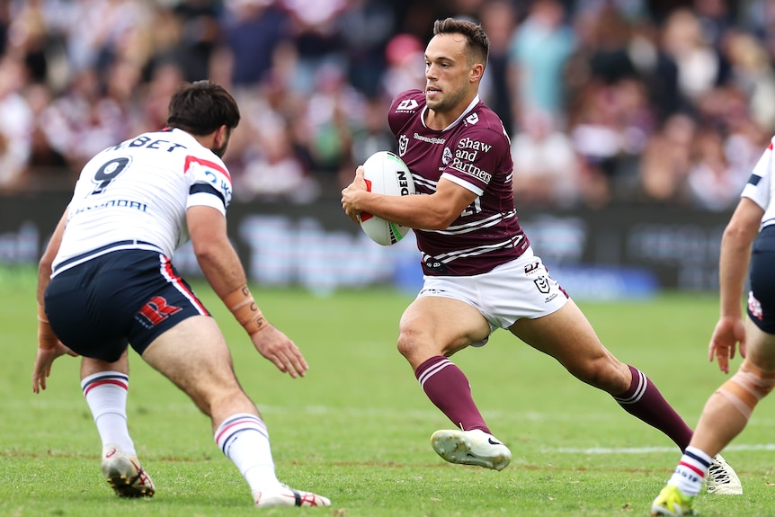 A man runs the ball during a rugby league match