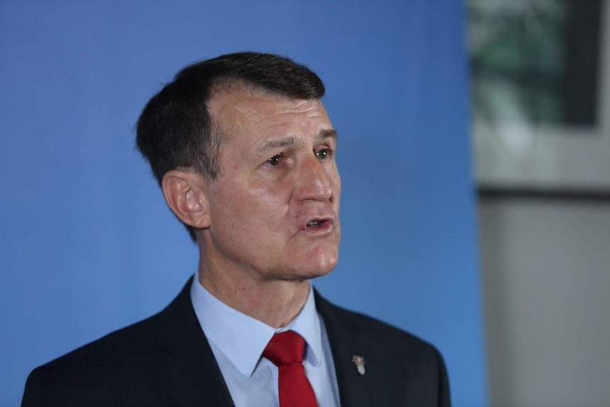 A man in a jacket and tie looking serious