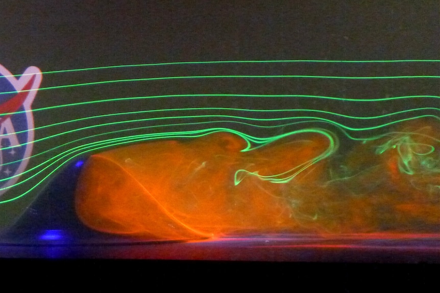 Axisymmetric hill surrounded by lasers and smoke. NASA logo in background.