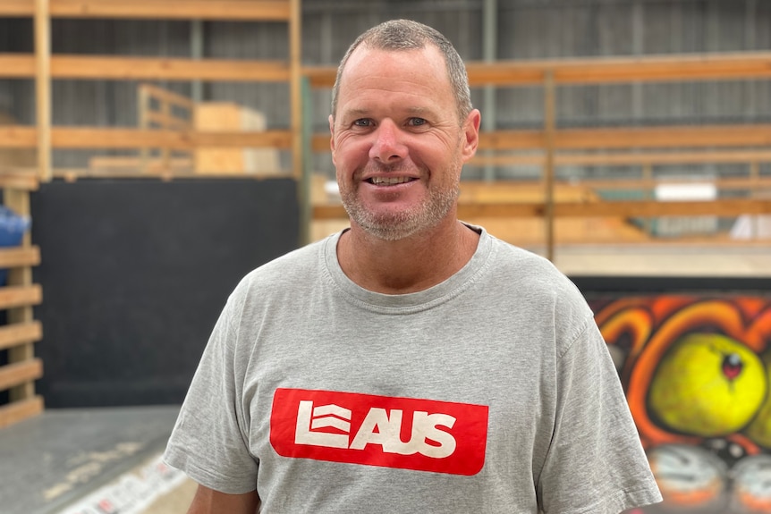 A man in a skateboarding facility smiling