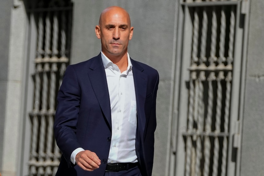 A man wearing a suit and shirt walking outside