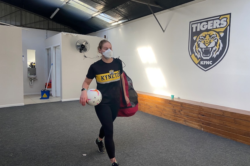 a photo of a girl walking out of a changeroom with netballs 