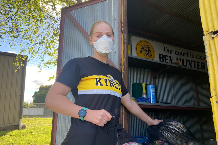 a photo of a girl putting netballs into a shed outside