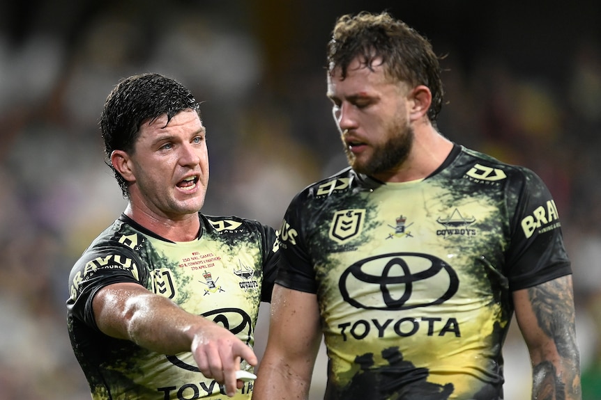 An NRL player talking to his teammate during a match, pointing and giving instructions