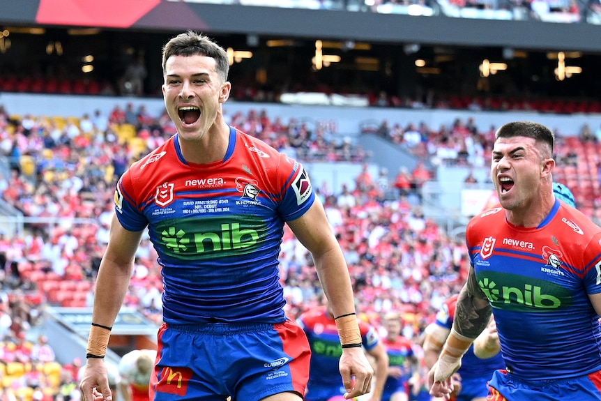 NRL players David Armstrong and Bradman Best cheering on field, looking at a crowd, after scoring.