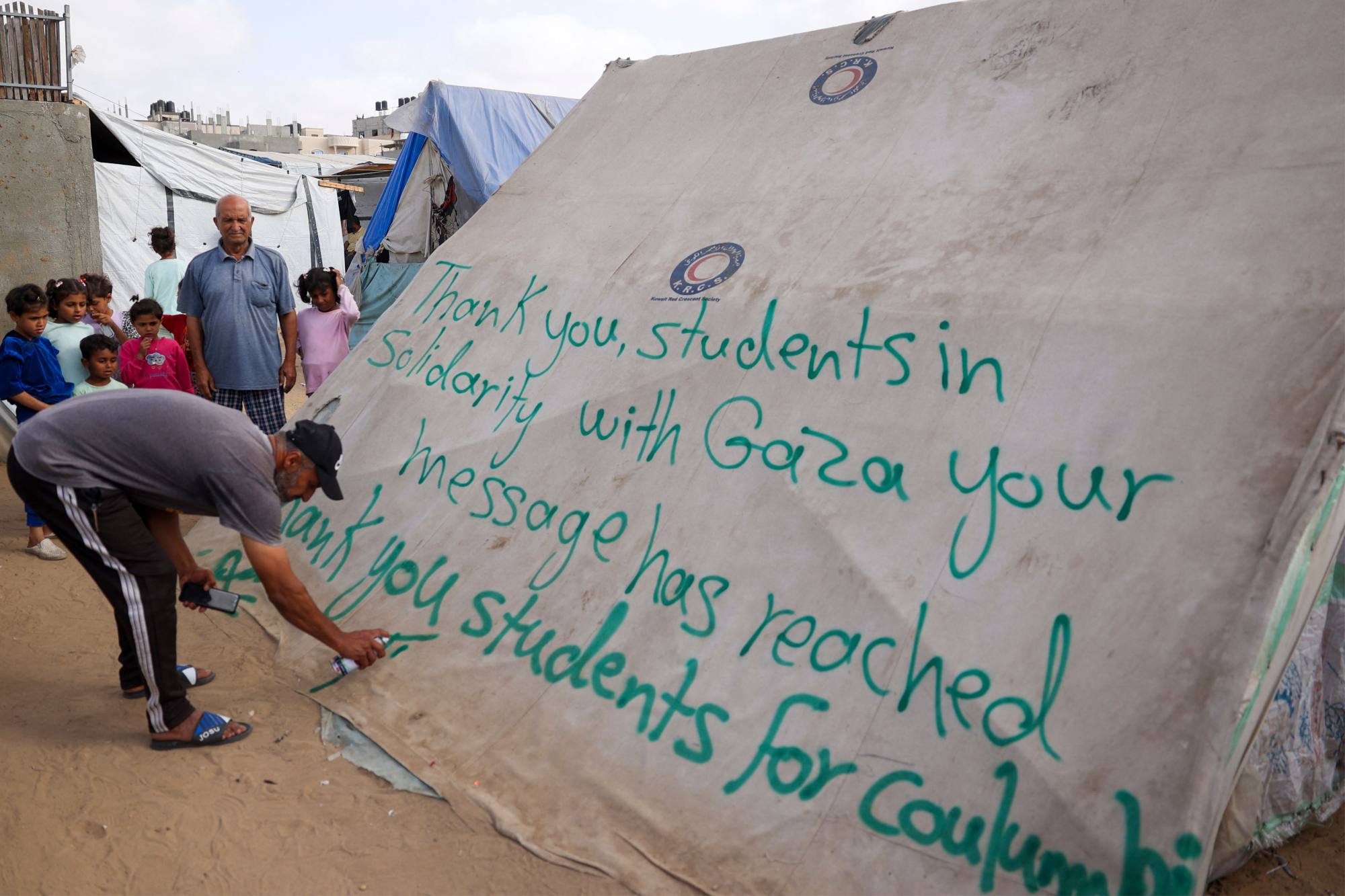 A man in Rafah, in the southern Gaza Strip, writes a message of thanks to students in the US. Photo: AFP