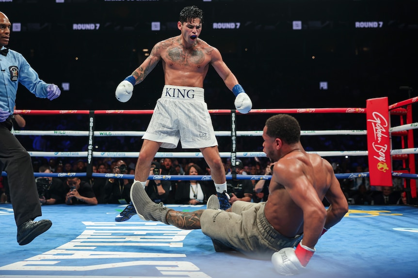 Boxer Ryan Garcia stands over and shouts at Devin Haney after knocking him down during a fight.