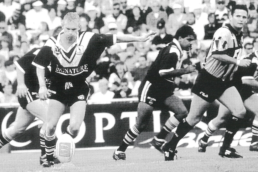 A man kicks off to begin a rugby league match
