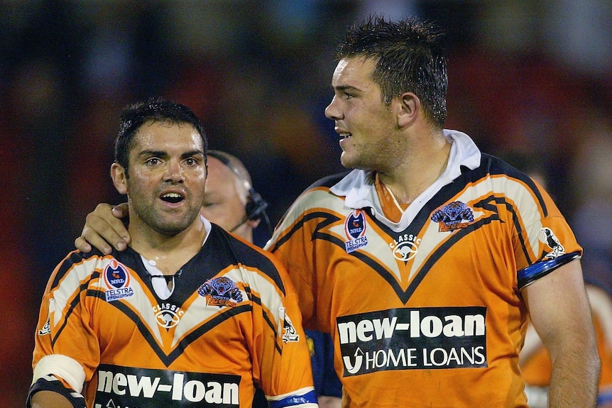 Two men celebrae after winning a rugby league match. 