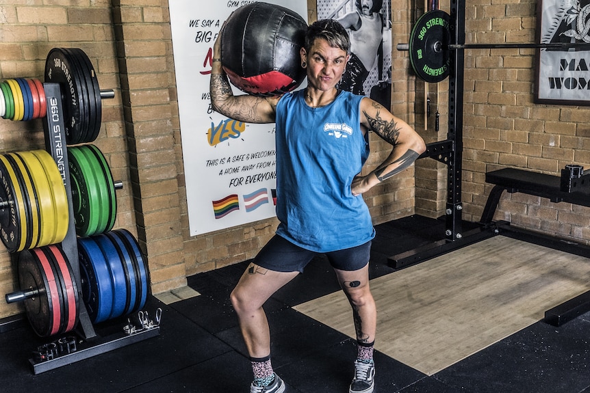 Ella Mason poses for a photo with a medicine ball on their shoulder, at Pony Club Gym in Melbourne.