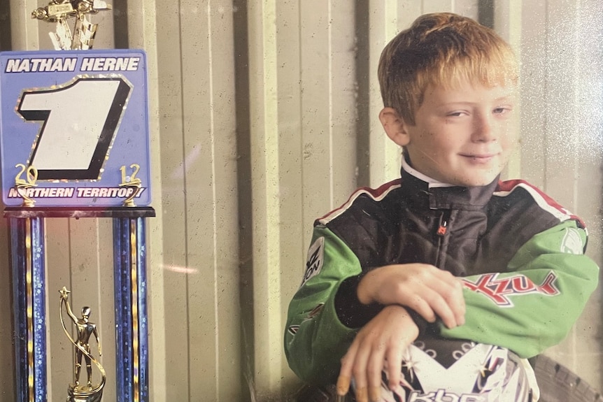 small boy with race tropy and helmet