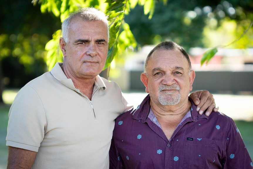 Russell Jeffrey and Brian Long stand arm in arm at a park in Darwin.