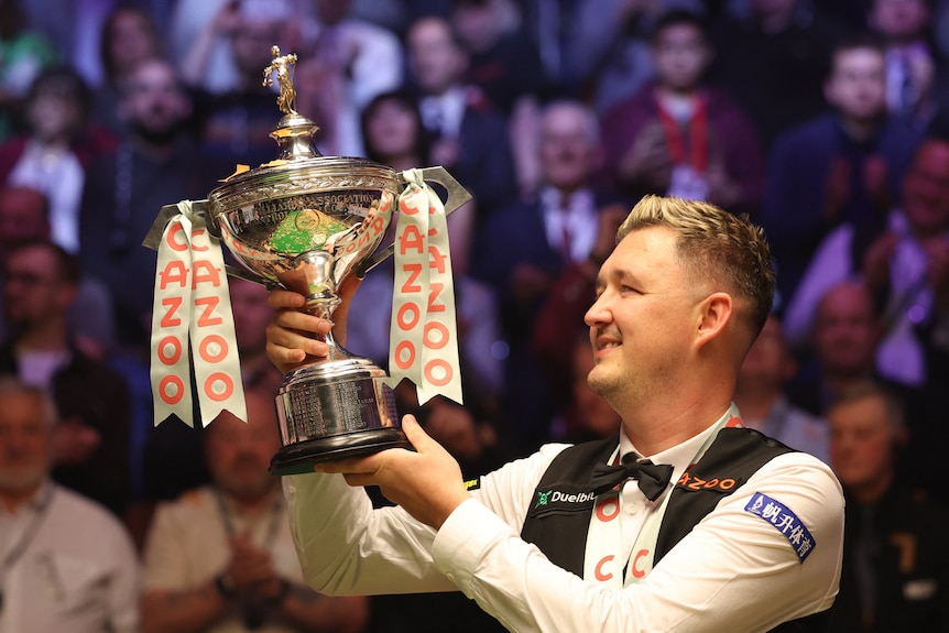Snooker player Kyren Wilson holding the World Snooker Championship trophy