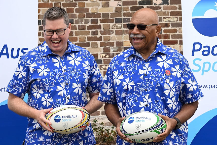 Two men holding rugby ball. 