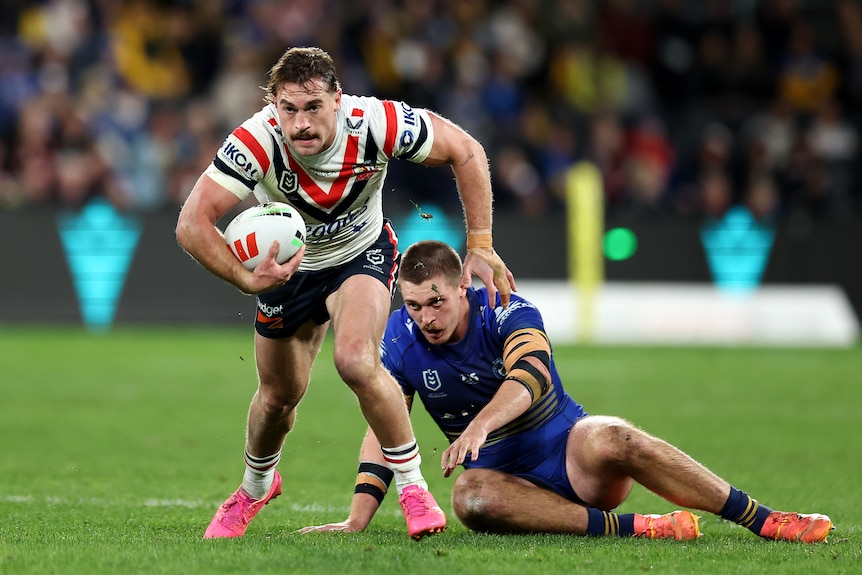 A man runs the ball during a rugby league match