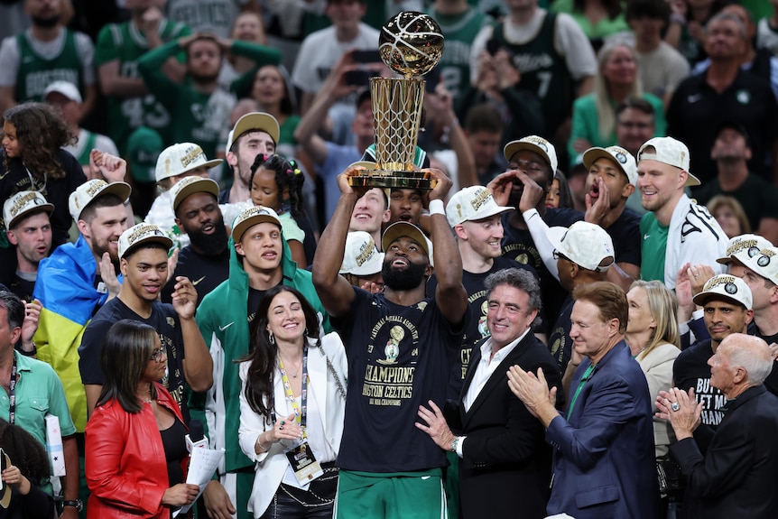 Jaylen Brown lifts the NBA trophy