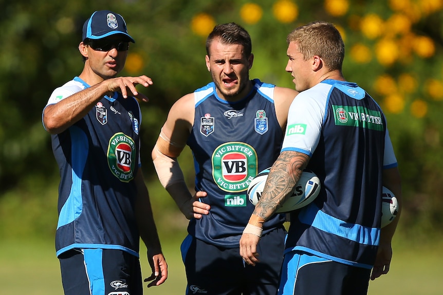 Two men talk to a coach during a rugby league training session