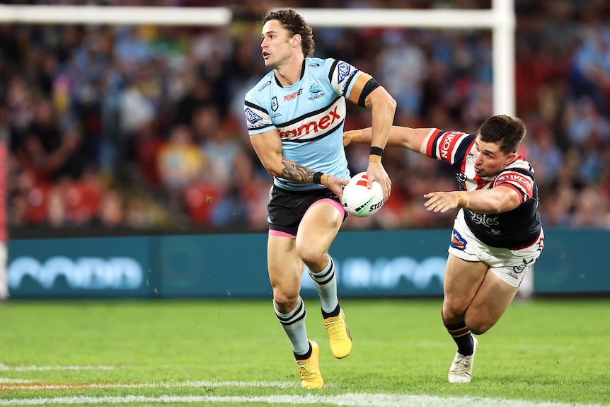 Nich Hynes of the Cronulla SHarks runs with the football as Sydney Roosters defender Victor Radley dives after him.