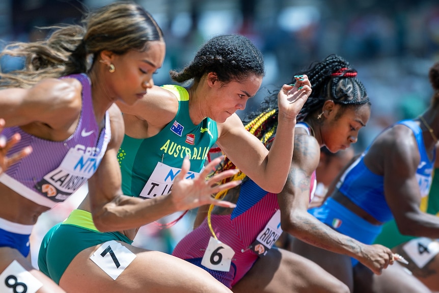 A line of female sprinters in national team leotards.