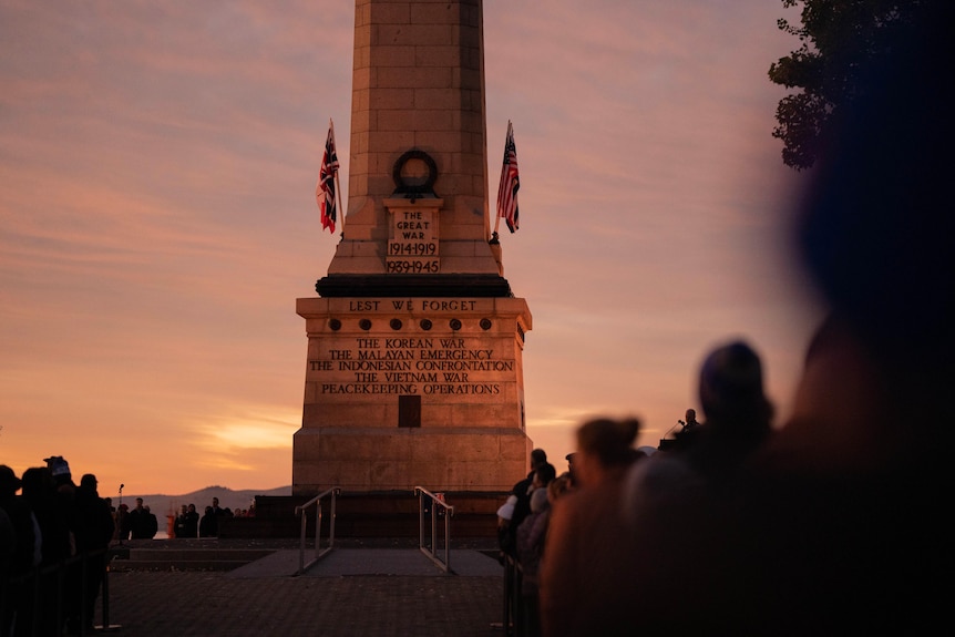 People line up in front of the Hobart Cenotaph in the early morning light.