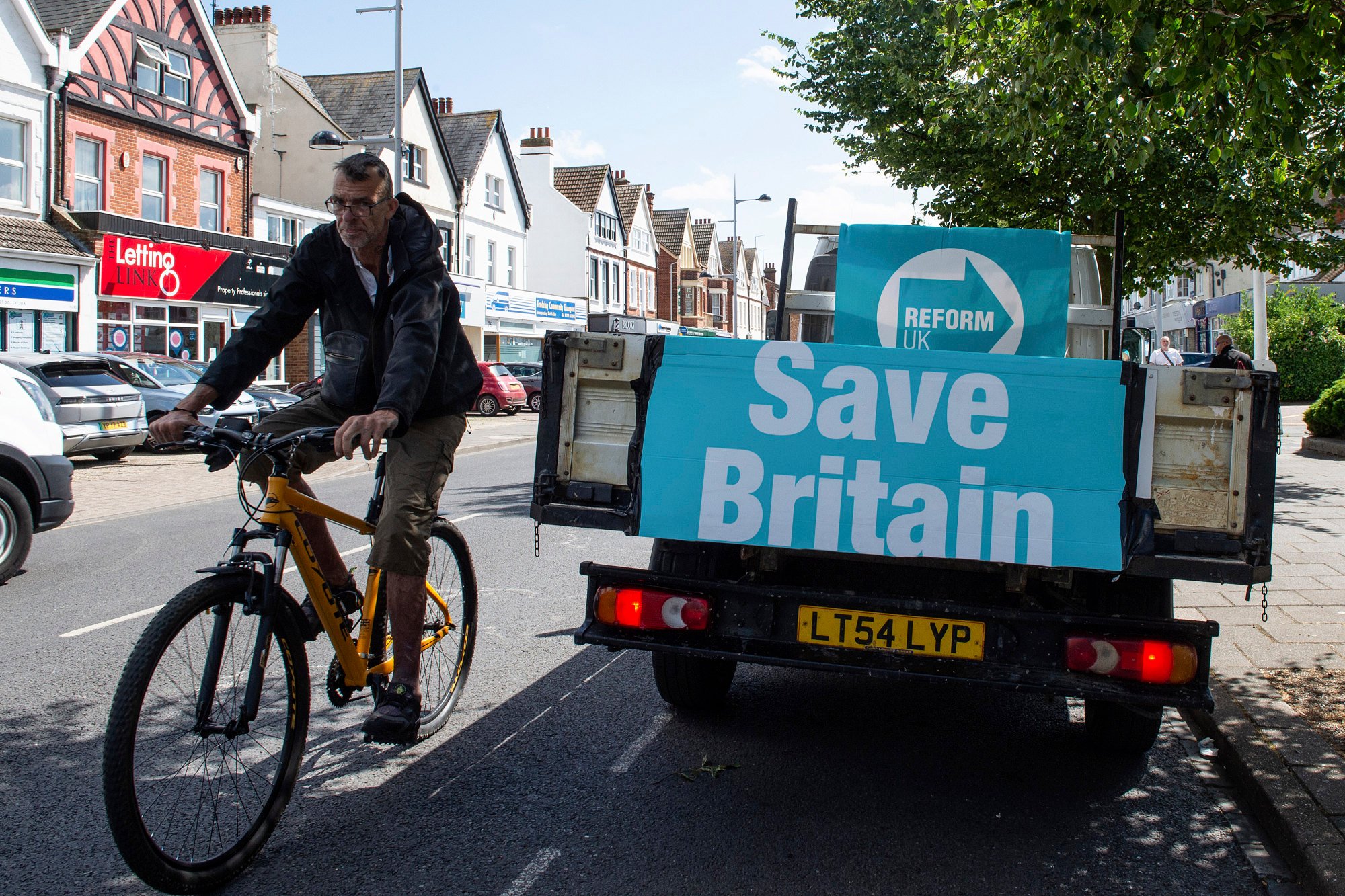 A cyclist passes a van with advertising for the Reform UK Party in Clacton On Sea, England on July 4. Photo: AP