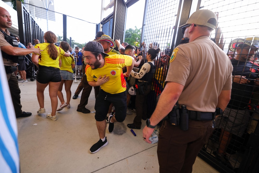 Fans rush the gates before to a stadium as security attempts to maintain order