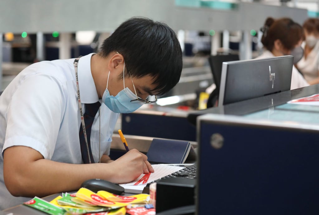 An employee of budget airline AirAsia uses pen and paper to take down passenger details at a check-in counter in the Hong Kong International Airport on Saturday, as a global outage affected Microsoft’s cloud computing services worldwide. Photo: Xiaomei Chen