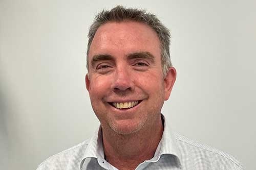 A man smiles in front of a white background