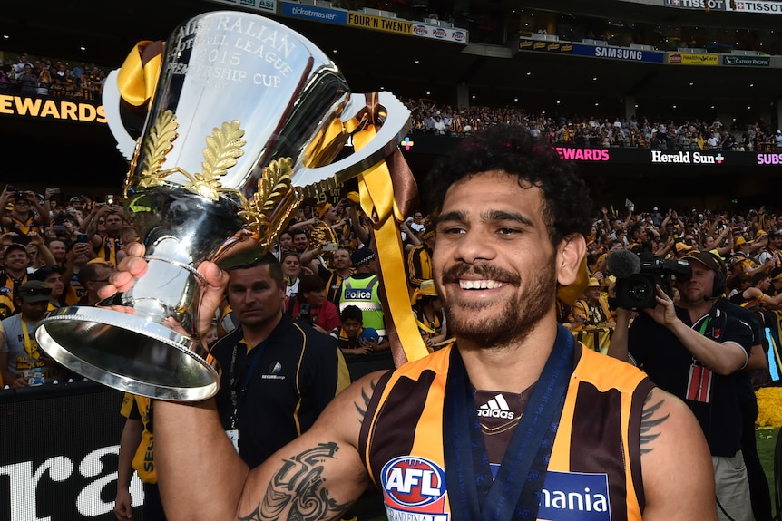  AFL player Cyril Rioli smiling, holding the AFL Premiership Cup, on the parade lap, after winning the grand final