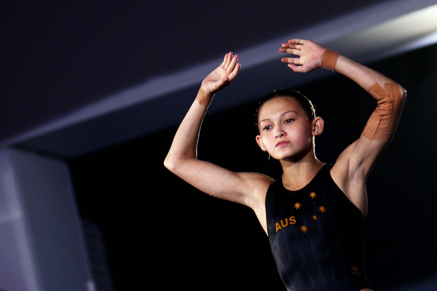 Diver Melissa Wu preparing to diver with hands above her head.