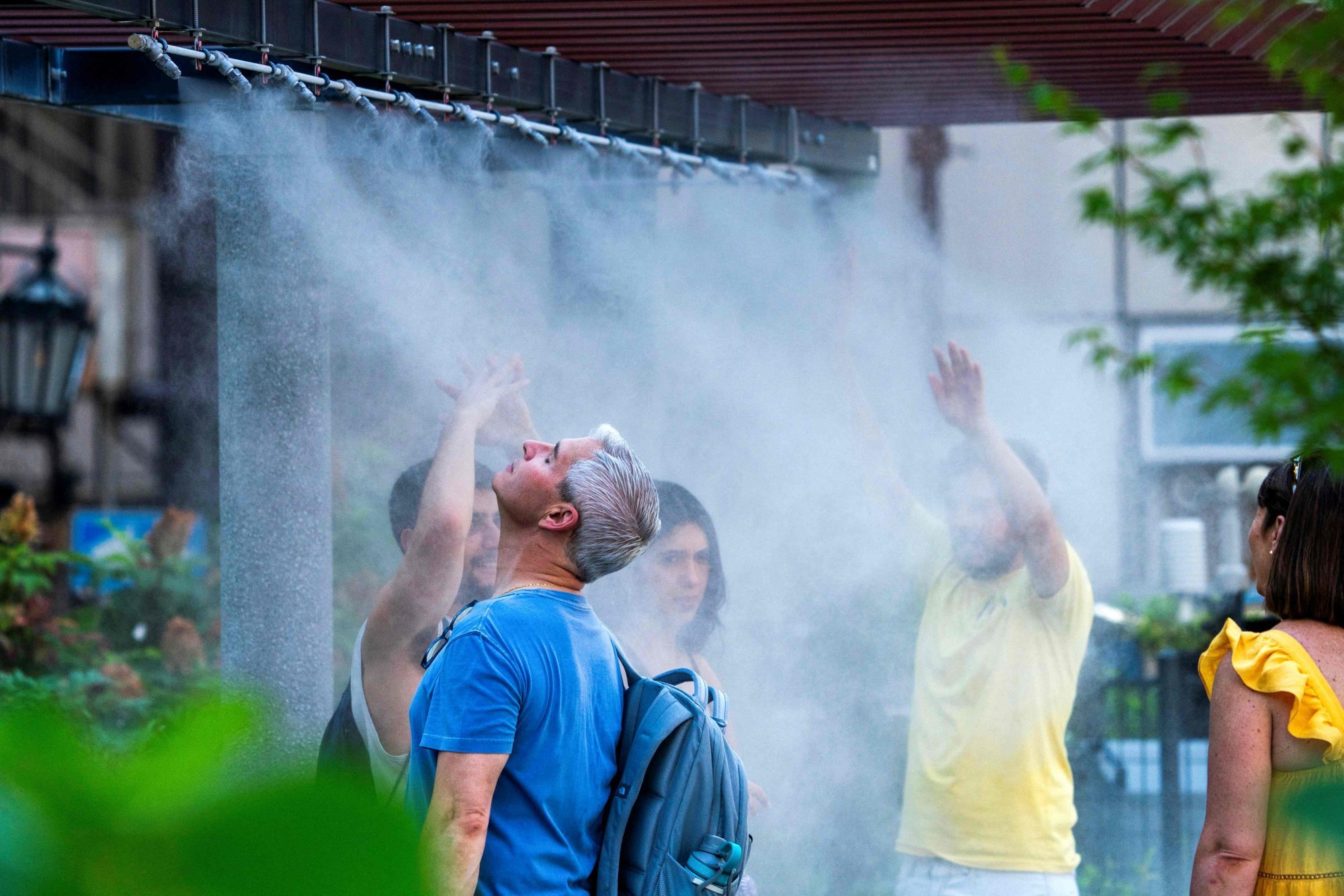 Tourists cool down under a mist shower in central Tokyo. Photo: AFP