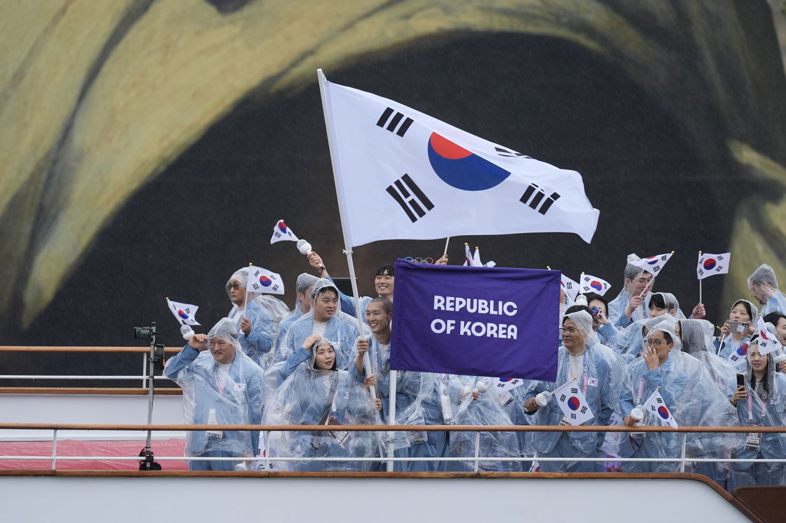 Repulic of Korea athletes on a boat flying a flag at opening ceremony of Olympic Games in Paris.