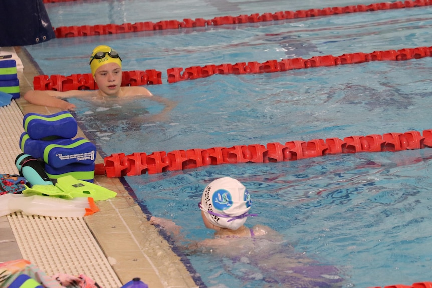 two swimmers look at each other at the end of their lanes