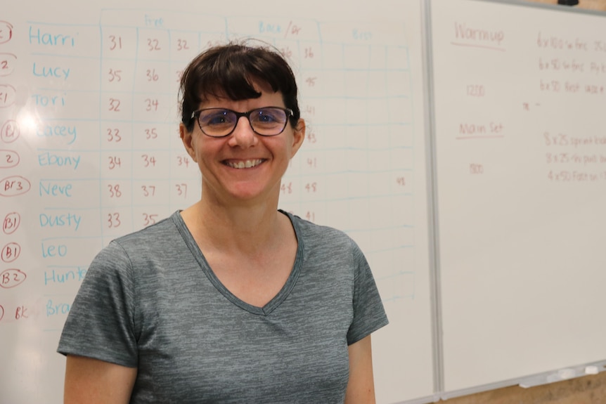 A woman with glasses smiles at the camera.