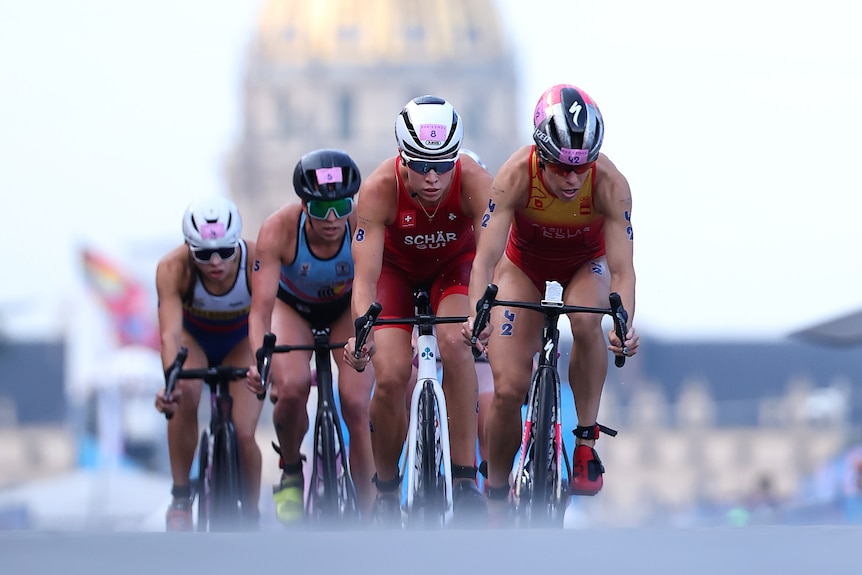 Triathletes ride a bike up a hill on Pont Alexandre III