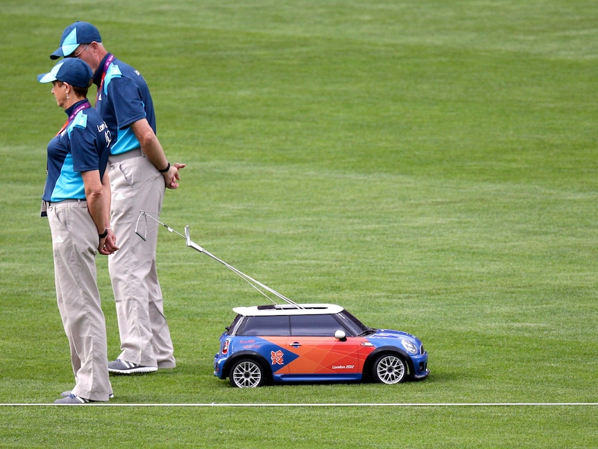 An RC that resembles a Mini Cooper drives away from Olympics officials with a javelin through its sunroof