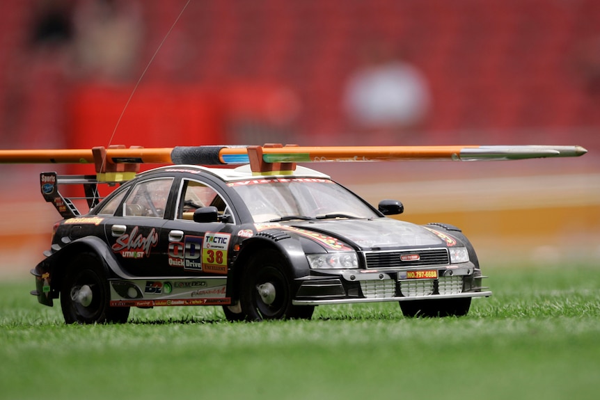 a black remote controlled car holing a javelin on its roof