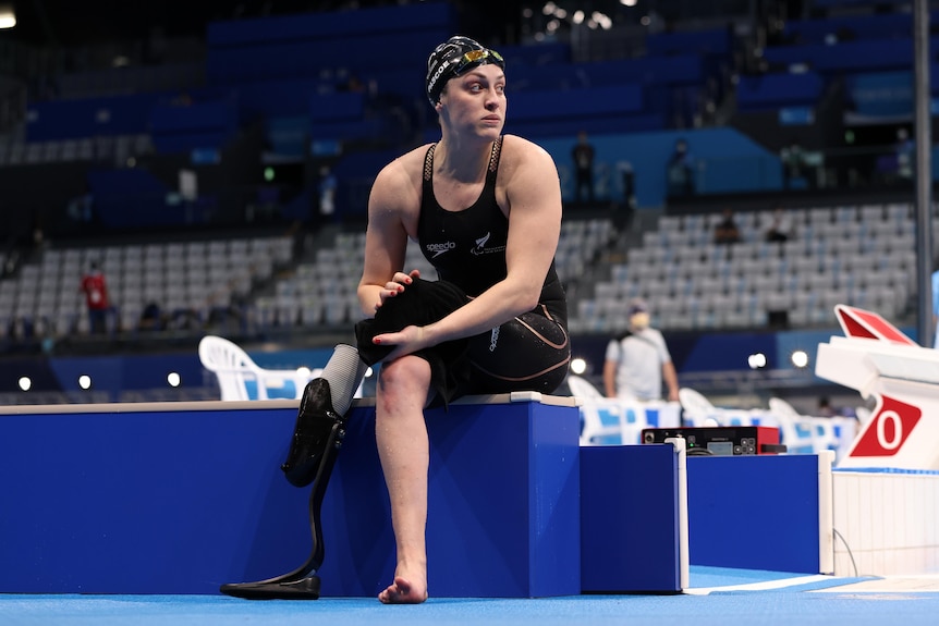 Sophie Pascoe sits on pool side drying her leg