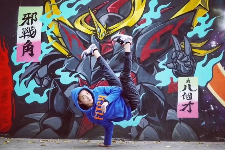 A man break dancing in front of a graffiti wall. 
