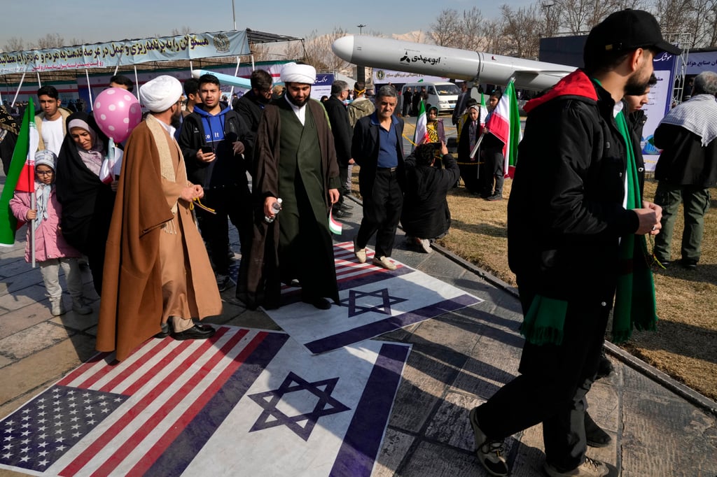Protesters walk on representations of the Israeli and US flags. Photo: AP