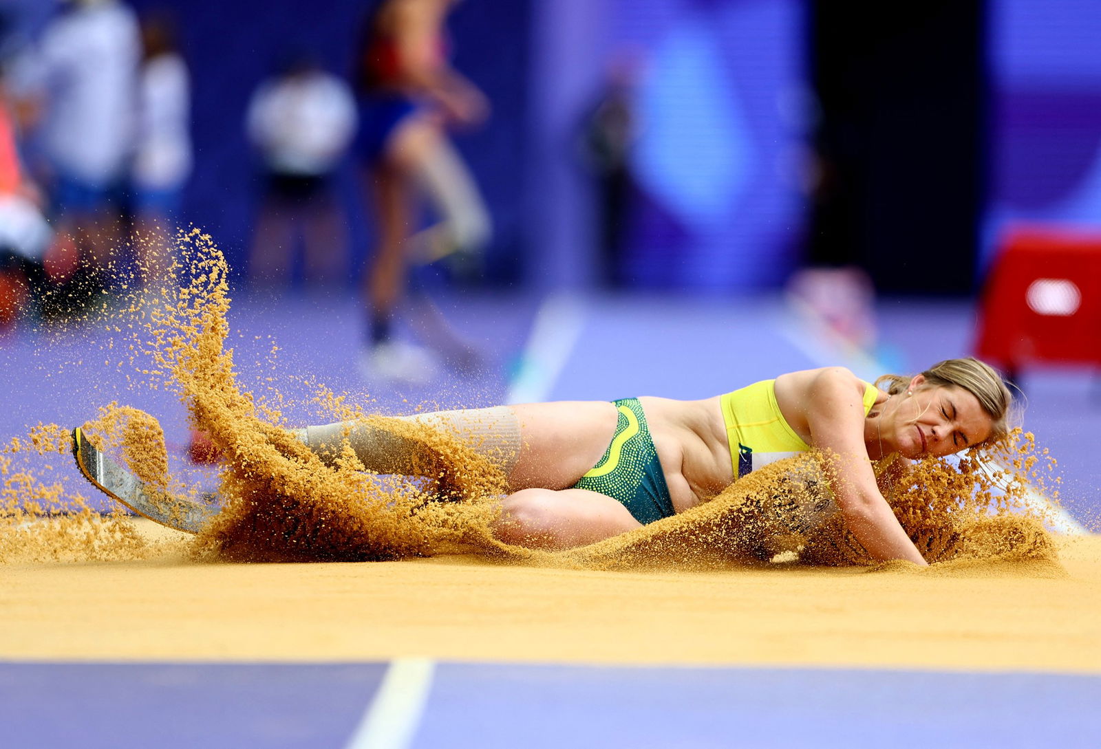 Australian long jumper Sarah Walsh is horizontal in the sand, after landing a jump. 