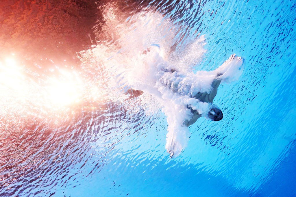 Man surrounded by bubbles after diving into pool